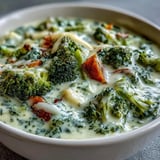 Creamy Broccoli Cheddar Soup with tender broccoli florets and shredded carrots in a rustic ceramic bowl.