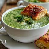 Photographed for a Contemporary American recipe blog, the golden pastries sit beside the steaming bowl, showcasing the soup's smooth texture and fresh thyme garnish.  