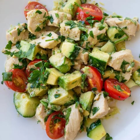 Avocado Chicken Salad with creamy avocado chunks, tender chicken, and fresh cherry tomatoes on a white plate.  