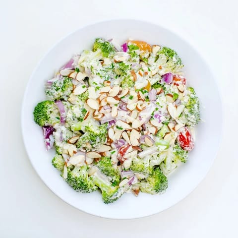 Fresh blanched broccoli salad with red onion, cherry tomatoes, and herbs, featuring a tangy garlic and Parmesan dressing, perfect as a light lunch.