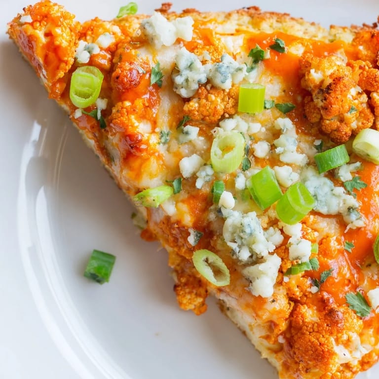 Sizzling hot Buffalo Cauliflower Pizza fresh from the oven, garnished with parsley and sliced green onions on a serving board.