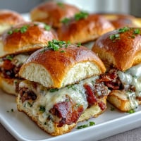 Miniature Derby Day Hot Brown sliders with turkey, bacon, and creamy Mornay sauce on soft Hawaiian rolls. Ideal for festive gatherings and Kentucky Derby celebrations.